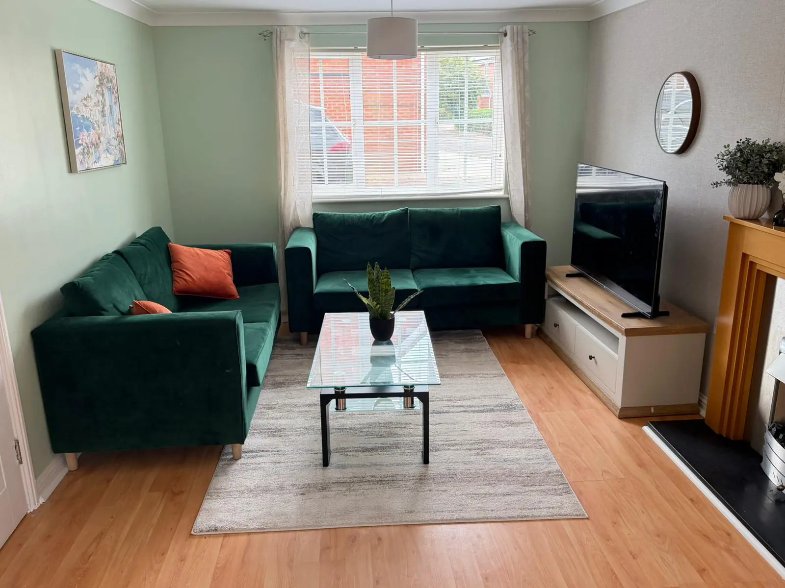 Lounge with green sofas, coffee table and television